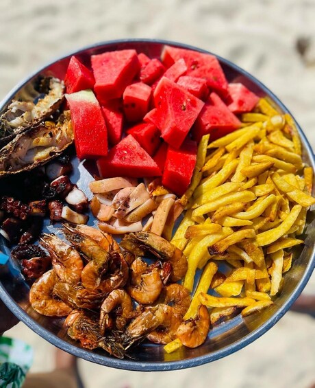 A seafood platter with shrimp, octopus, and squid, alongside watermelon cubes and French fries. 4