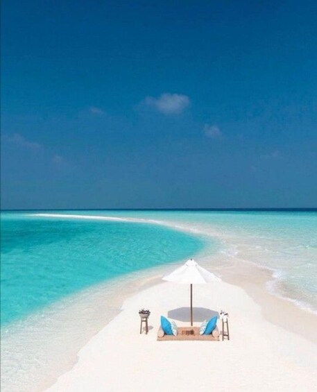 A beach with a white umbrella and lounge chair, clear turquoise water, and a sandy shore. 5
