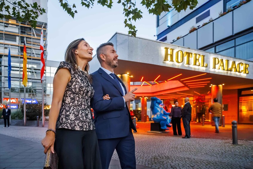A couple standing in front of a building with a sign that reads 'HOTEL PALACE'. 3