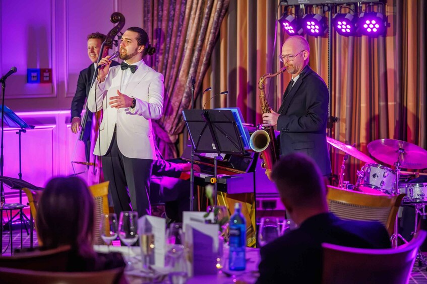 A jazz band performing on stage with a saxophonist and a pianist, seated audience in the foreground. 4