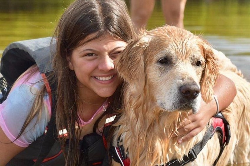 En person i redningsvest omfavner en gylden labrador. 4