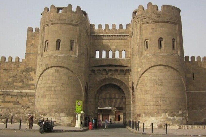 A historic stone castle with two round towers and a large arched entrance. 1