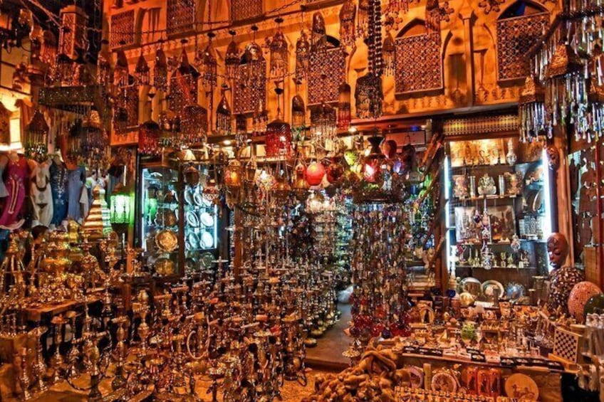 A densely packed indoor market with various stalls selling items like jewelry, pottery, and textiles. 4