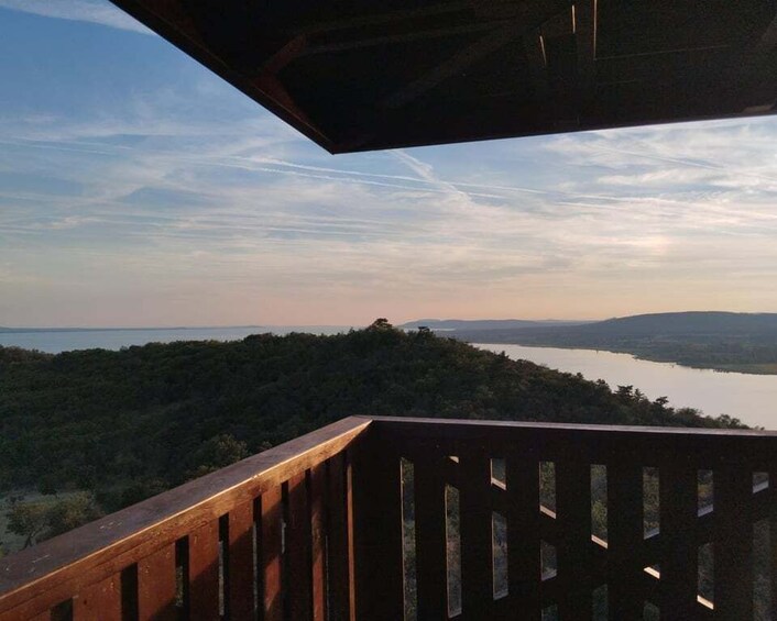 A wooden deck overlooking a lake surrounded by hills. 1