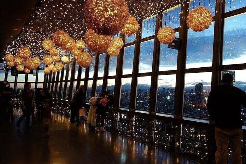 A spacious indoor area with large windows, decorative spherical light fixtures, and a cityscape view. 3