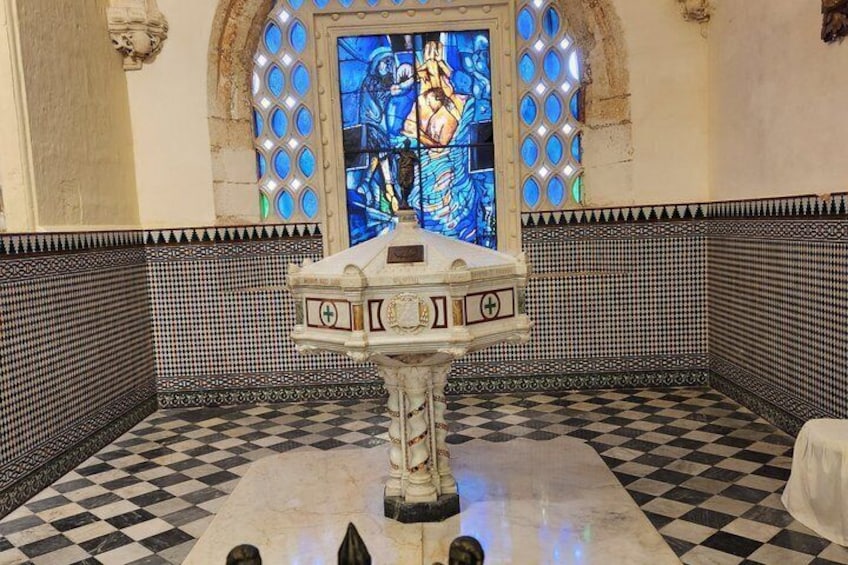 Een kapel met een schaakbordvloer, een centraal altaar en een glas-in-loodraam met een religieuze figuur. 5
