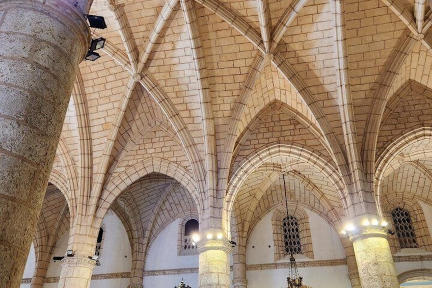 Een kathedraalinterieur met gewelfde plafonds en stenen zuilen. 3