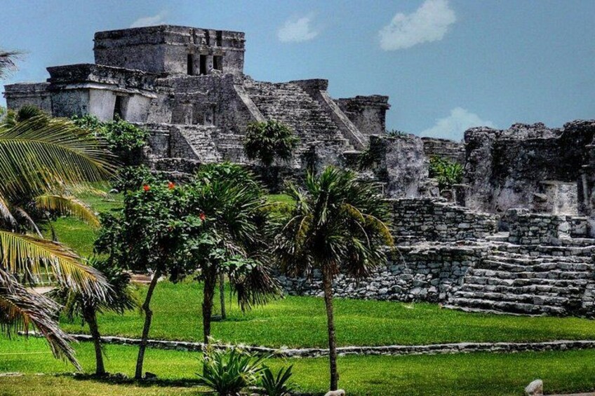 Ancient ruins with a pyramid structure, palm trees, and a grassy area. 5