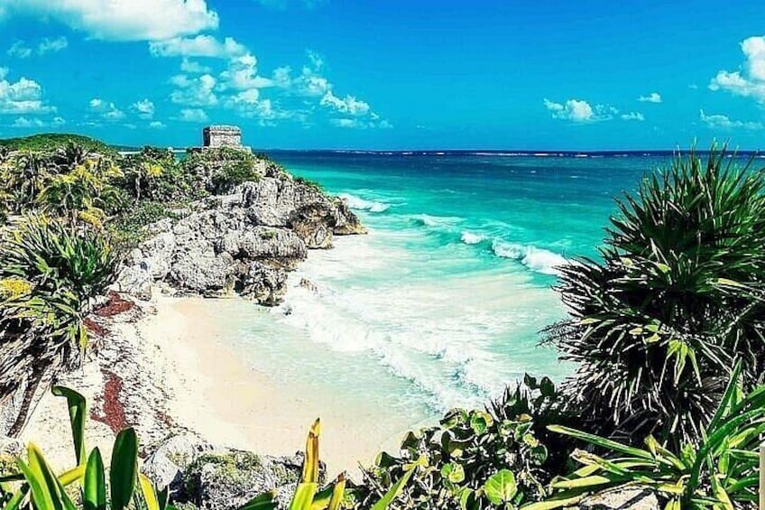 A coastal landscape with a beach, ocean, and a structure on a cliff. 3