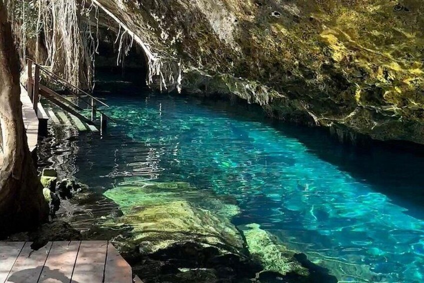 A clear blue pool with a wooden deck and a rocky cave wall. 2