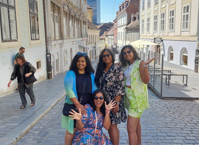 A group of people posing on a cobblestone street with historic buildings. 1