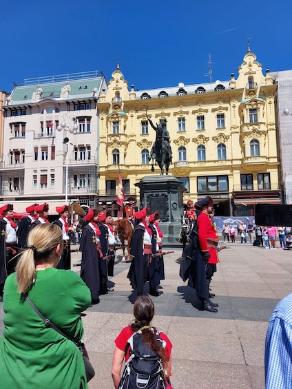A group of people in uniform standing in front of a building with a statue. 5