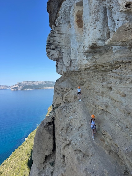 A person rock climbing a steep cliff by the sea. 4