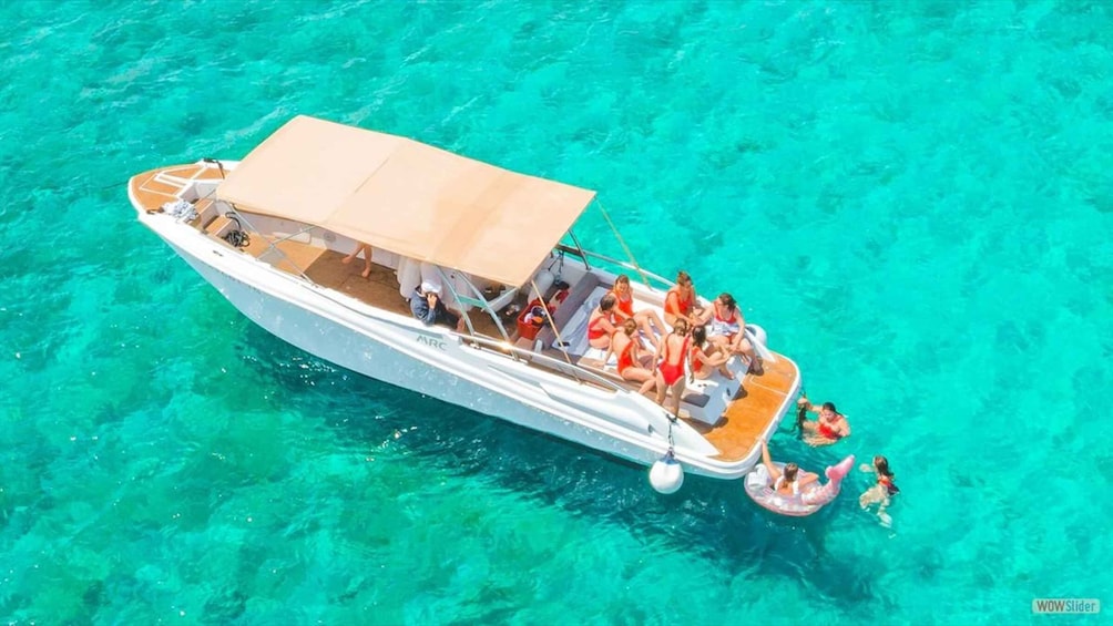A boat with people on board, floating on clear turquoise water. 1