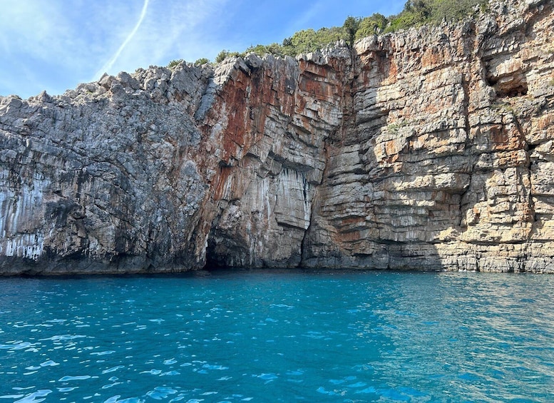 A rocky cliff by a clear blue sea. 4