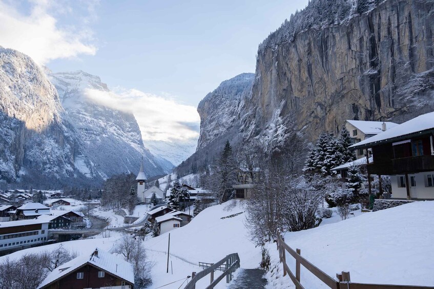 A snow-covered village with houses, a church, and mountains in the background. 5
