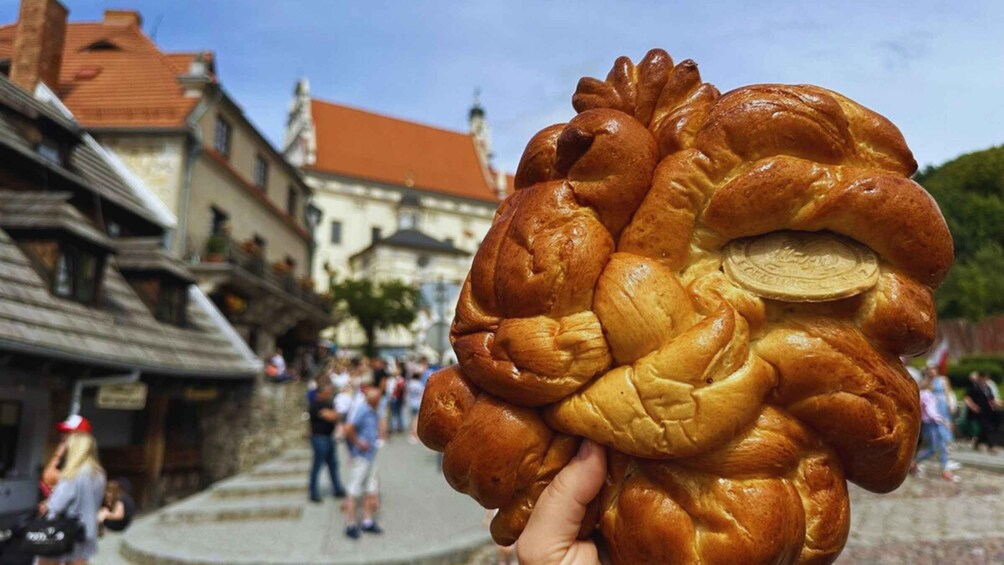 A person holding a braided bread with a coin in the center. 1