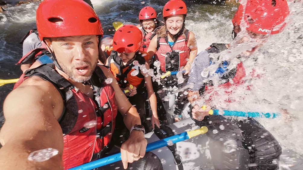 A group of people rafting on a river, wearing helmets and life jackets. 1