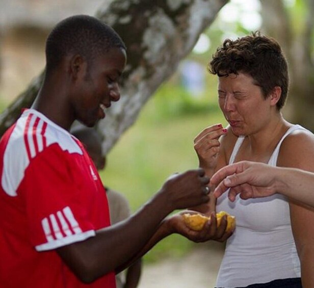 A person in a red and white jersey handing food to another person. 1