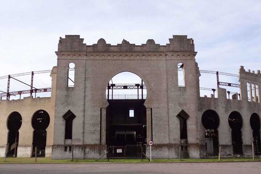 A large, historic stone building with arched doorways and a central archway. 2