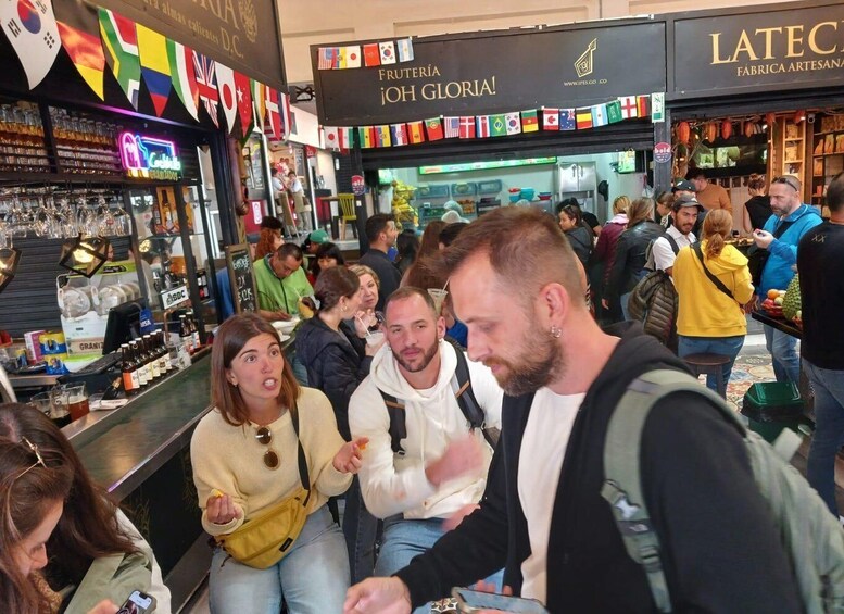 A crowded indoor market with various stalls selling food and drinks. 5