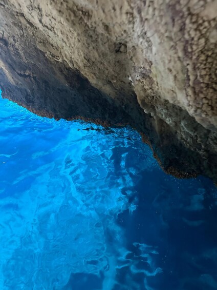 A cave opening with clear blue water inside. 4
