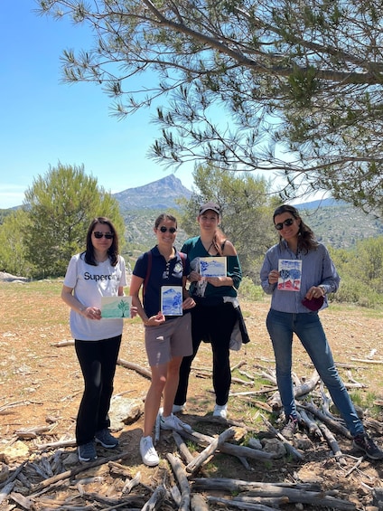 Four people standing on a forested hillside with a mountain in the background. 3