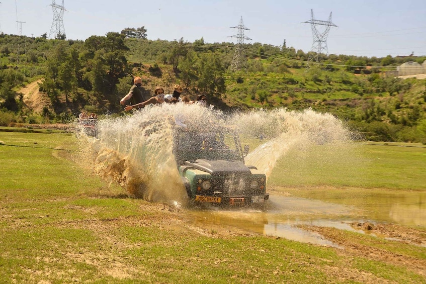 A vehicle driving through a puddle, splashing water. 5