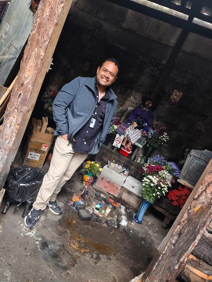 A man standing in a cluttered shop with flowers and various items on display. 1