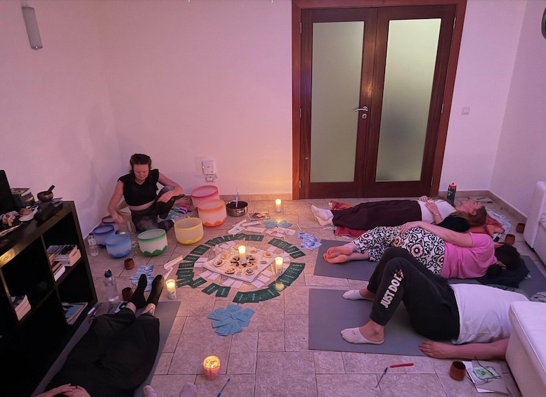 A group of people engaged in a card game on the floor, surrounded by candles and bowls. 4