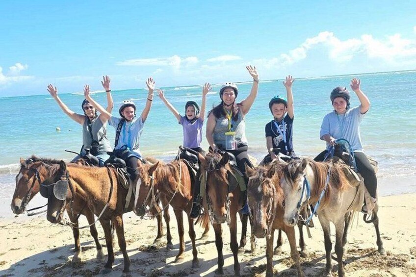 A group of people on horseback on a beach with the ocean in the background. 4