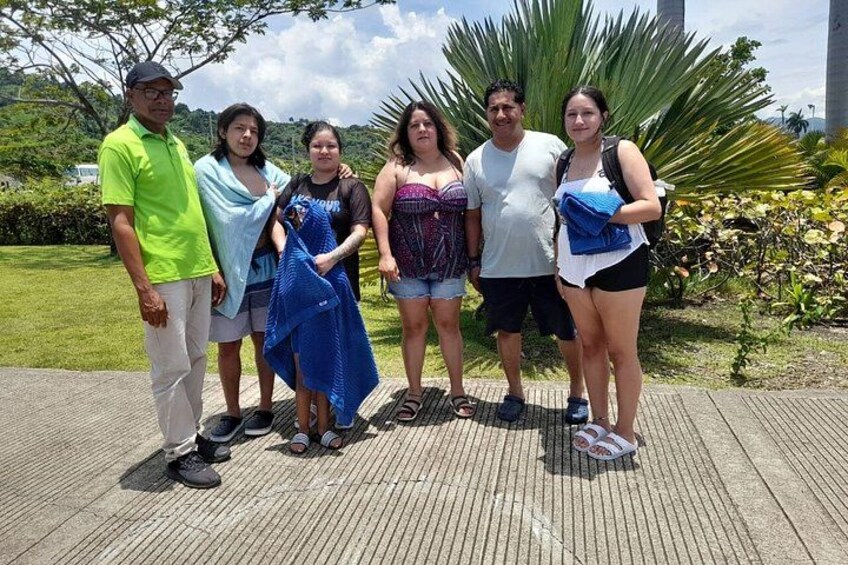 A group of people standing on a paved area with greenery and palm trees in the background. 2