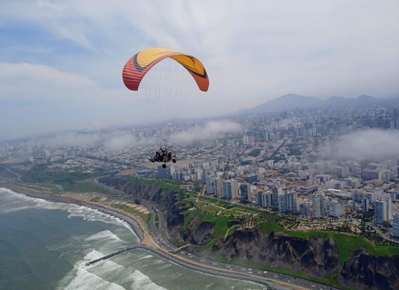 Un parapente vuela sobre una ciudad costera con vistas al océano y a los acantilados. 3