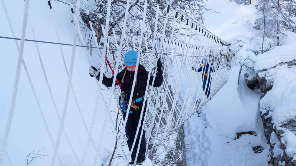 A person crossing a snowy suspension bridge. 5