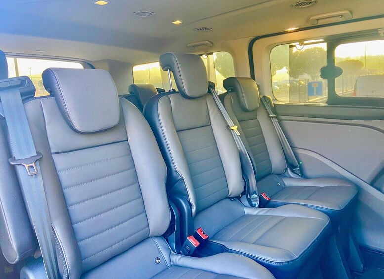 A vehicle interior with three rows of seats, seat belts, and a sunroof. 2