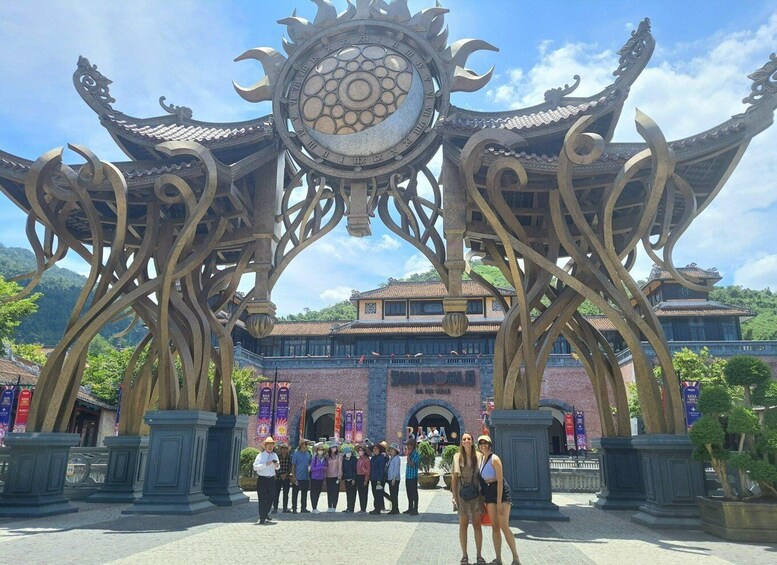 A traditional gate with ornate metalwork and a circular emblem, leading to a building with a tiled roof. 4
