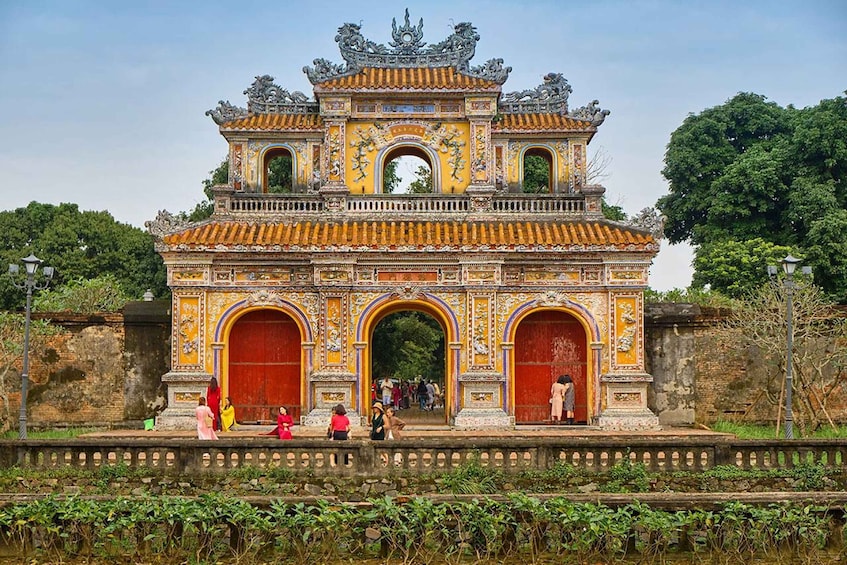 A traditional Vietnamese gate with ornate decorations and two large red doors. 2