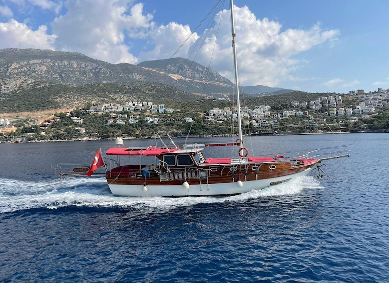 A wooden boat with a red canopy sailing on a calm sea. 1
