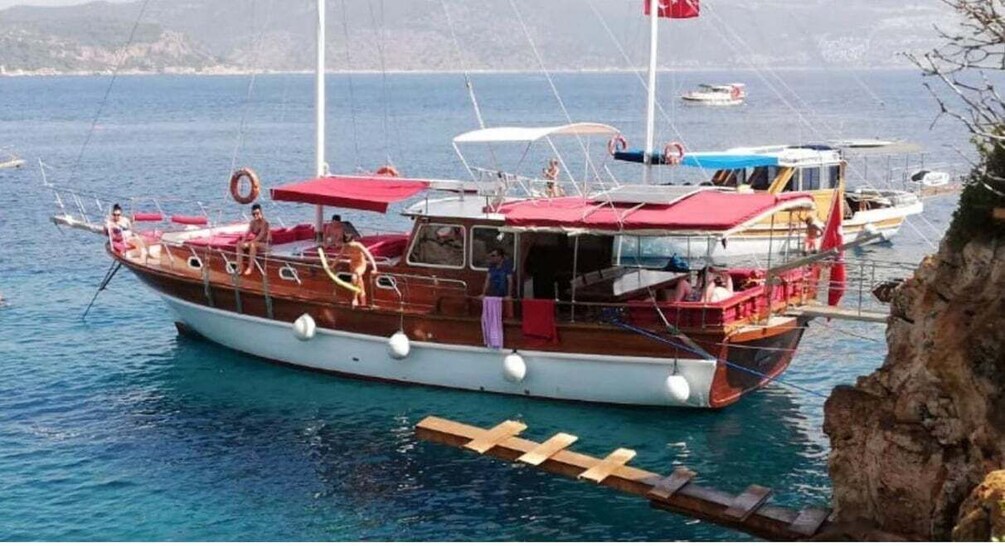 A wooden boat with a red canopy docked at a pier. 5
