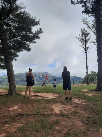 A group of people standing on a grassy hill overlooking a mountainous landscape. 4