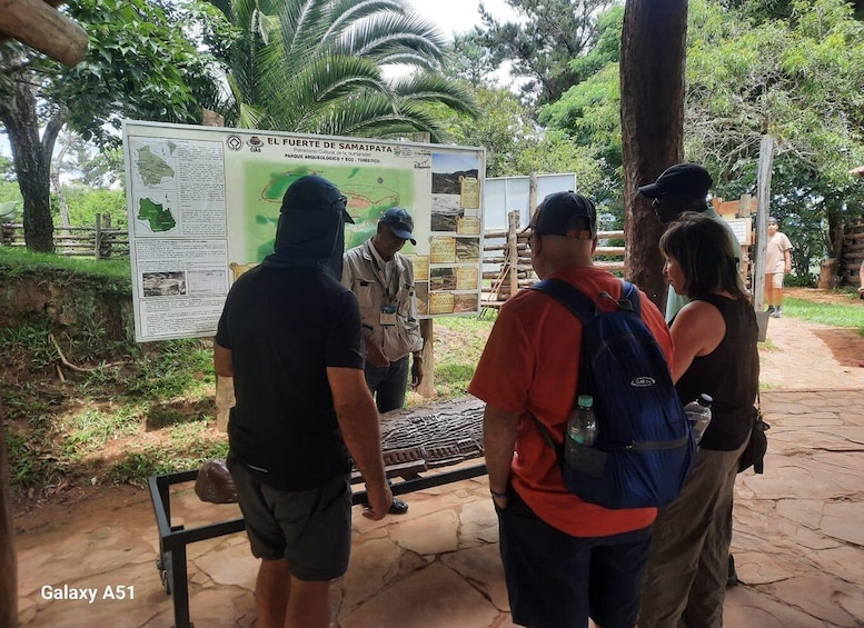 A group of people at a park information board with maps and text. 2