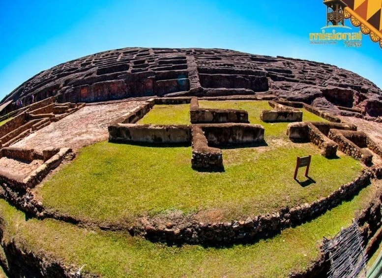 An ancient amphitheater with stone seating and a grassy central area. 1