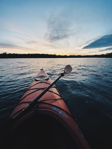 A kayak on calm water with a sunset in the background. 1
