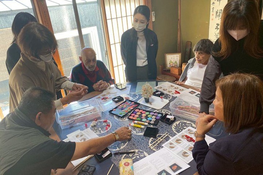 A group of people sitting around a table with various items like cards, a mobile phone, and papers. 5