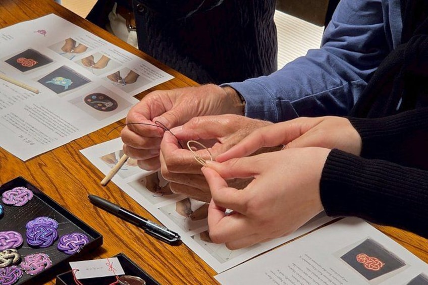 Hands assembling a craft with wire and paper instructions. 2