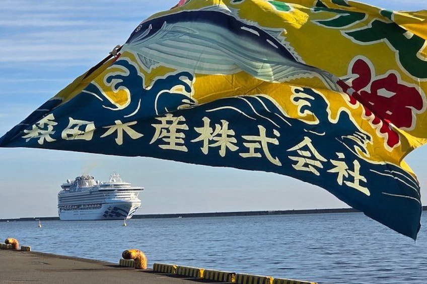 A large sail with Chinese characters, a cruise ship, and a calm sea. 4
