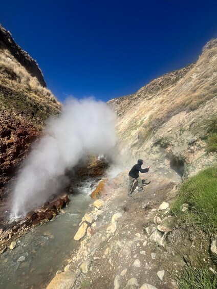 A person standing near a steam vent with a flowing stream. 3