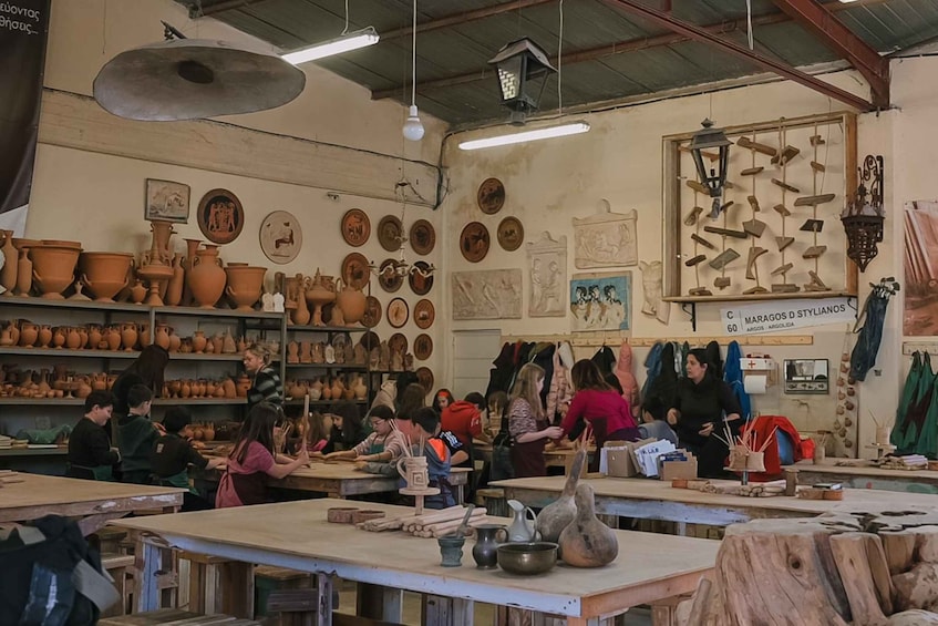A pottery workshop with shelves of clay pots and people working at tables. 3