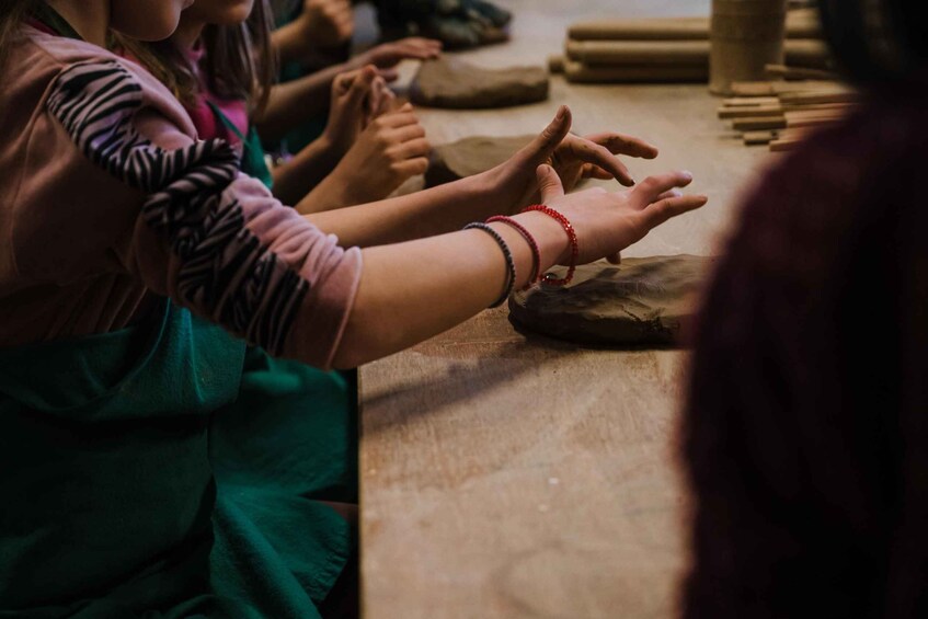 A group of people engaged in a craft activity, possibly pottery, with clay and tools on a table. 5