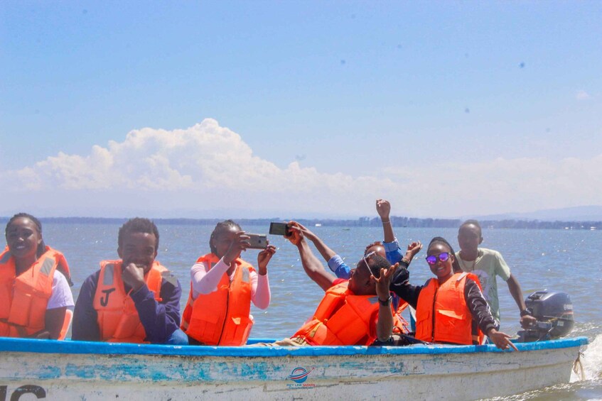 People in a boat wearing orange life jackets, taking photos. 5